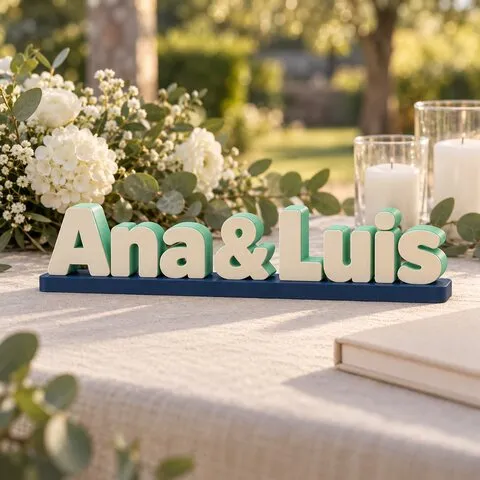 El letrero Ana & Luis en letras crema con cantos menta, sobre una base azul marino en la mesa de bienvenida de una boda.