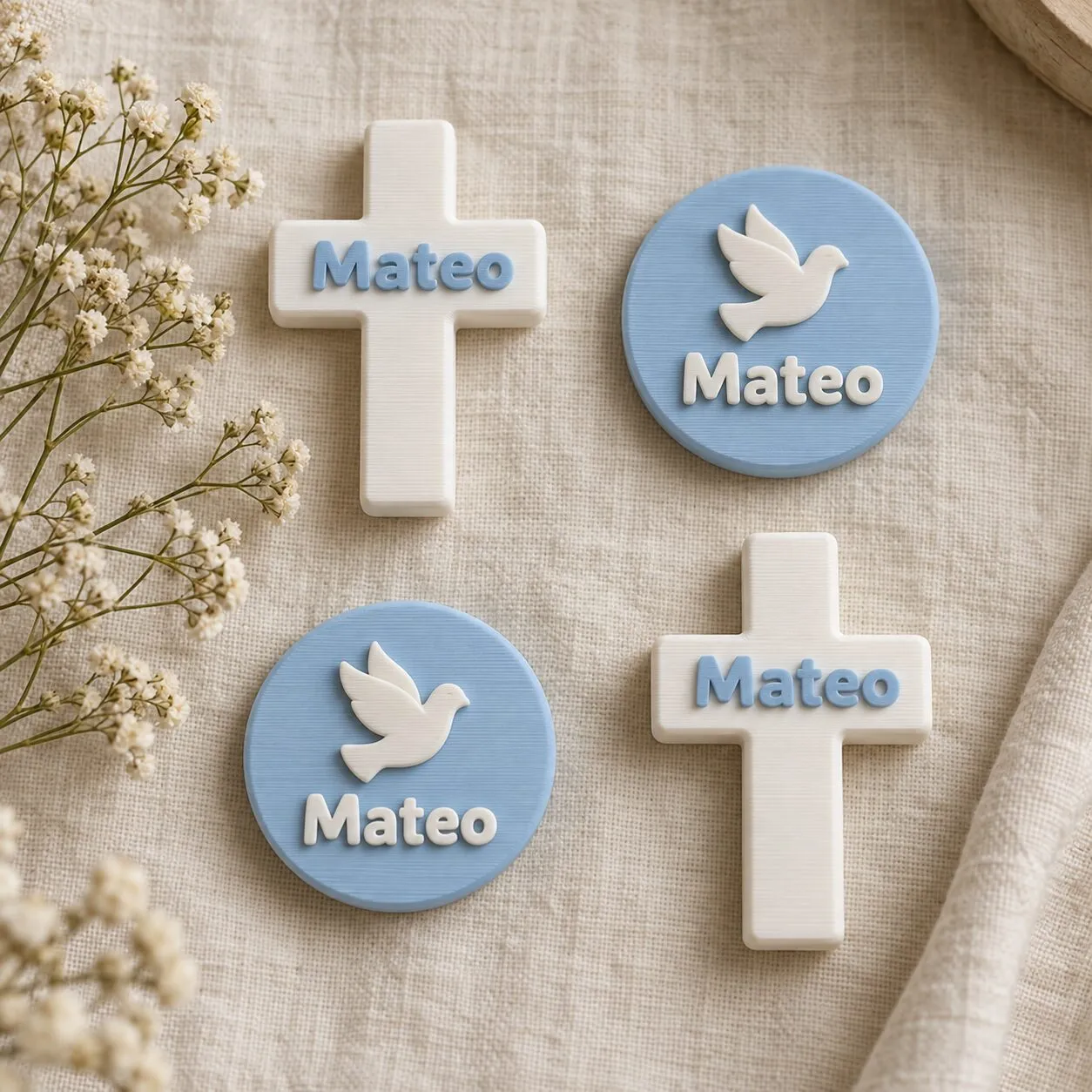 Cuatro recuerdos de bautizo con el nombre Mateo: dos cruces blancas y dos piezas redondas celestes con una paloma.